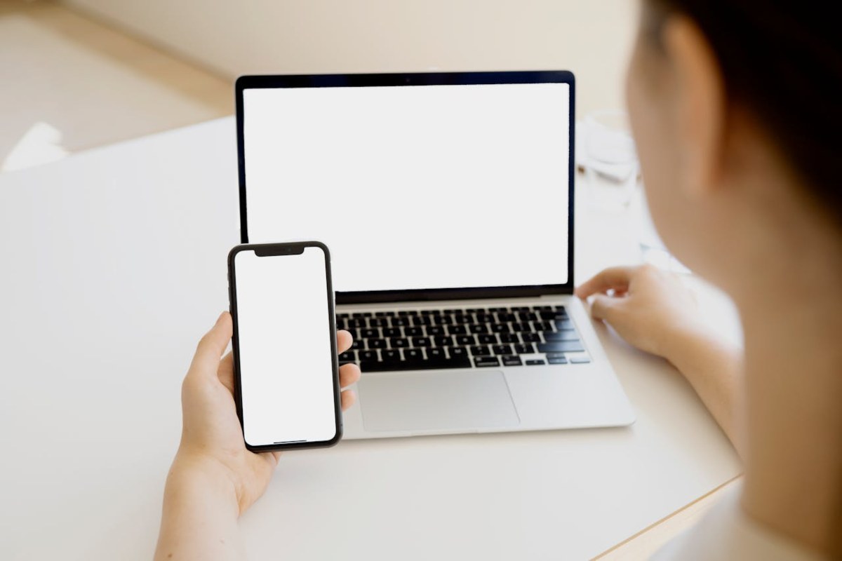 Persona con laptop e smartphone accesi