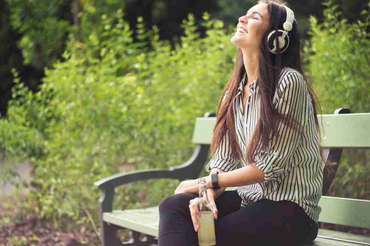 ragazza su una panchina ascolta podcast tramite app