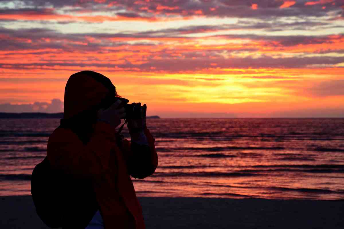 sagoma controluce di persona che vuole fotografare il tramonto in modo professionale