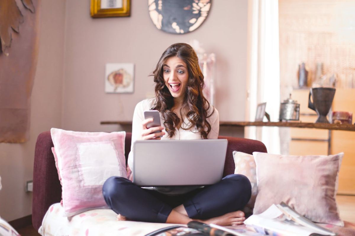 Ragazza sorridente allo smartphone e al laptop