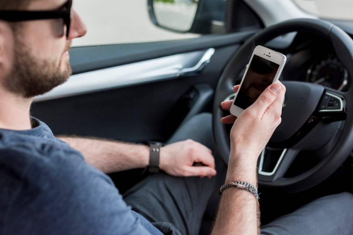 Uomo alla macchina con il telefono in mano