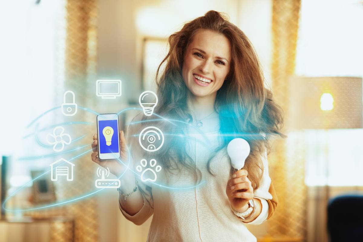 Donna sorridente con smartphone e lampadina in mano