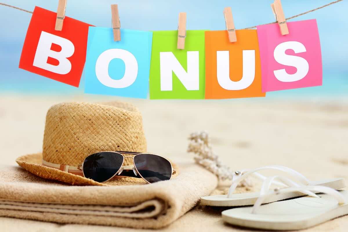 Scritta bonus, cappello di paglia, occhiali da sole, telo, infradito su spiaggia di sabbia
