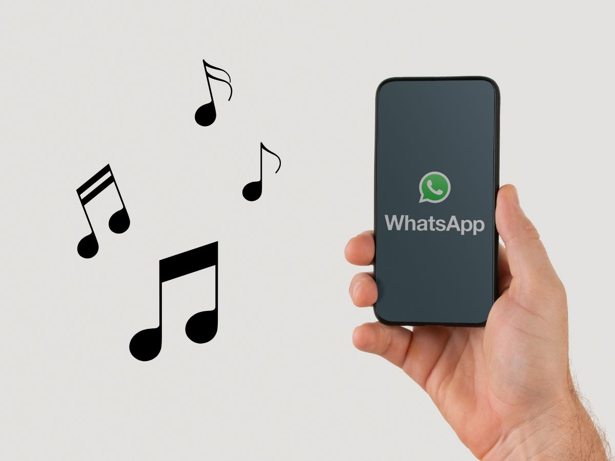 note musicali accanto a una mano che regge uno smartphone con logo WhatsApp