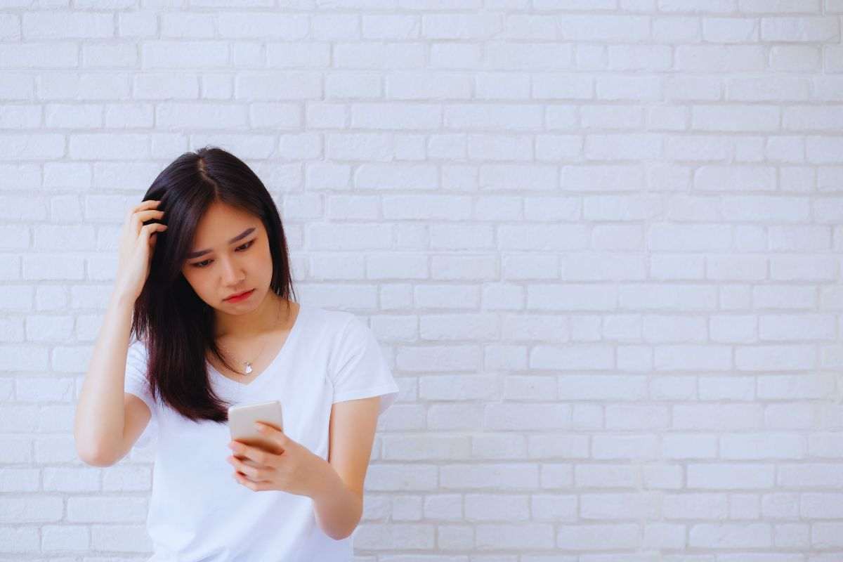 Donna perplessa che guarda smartphone
