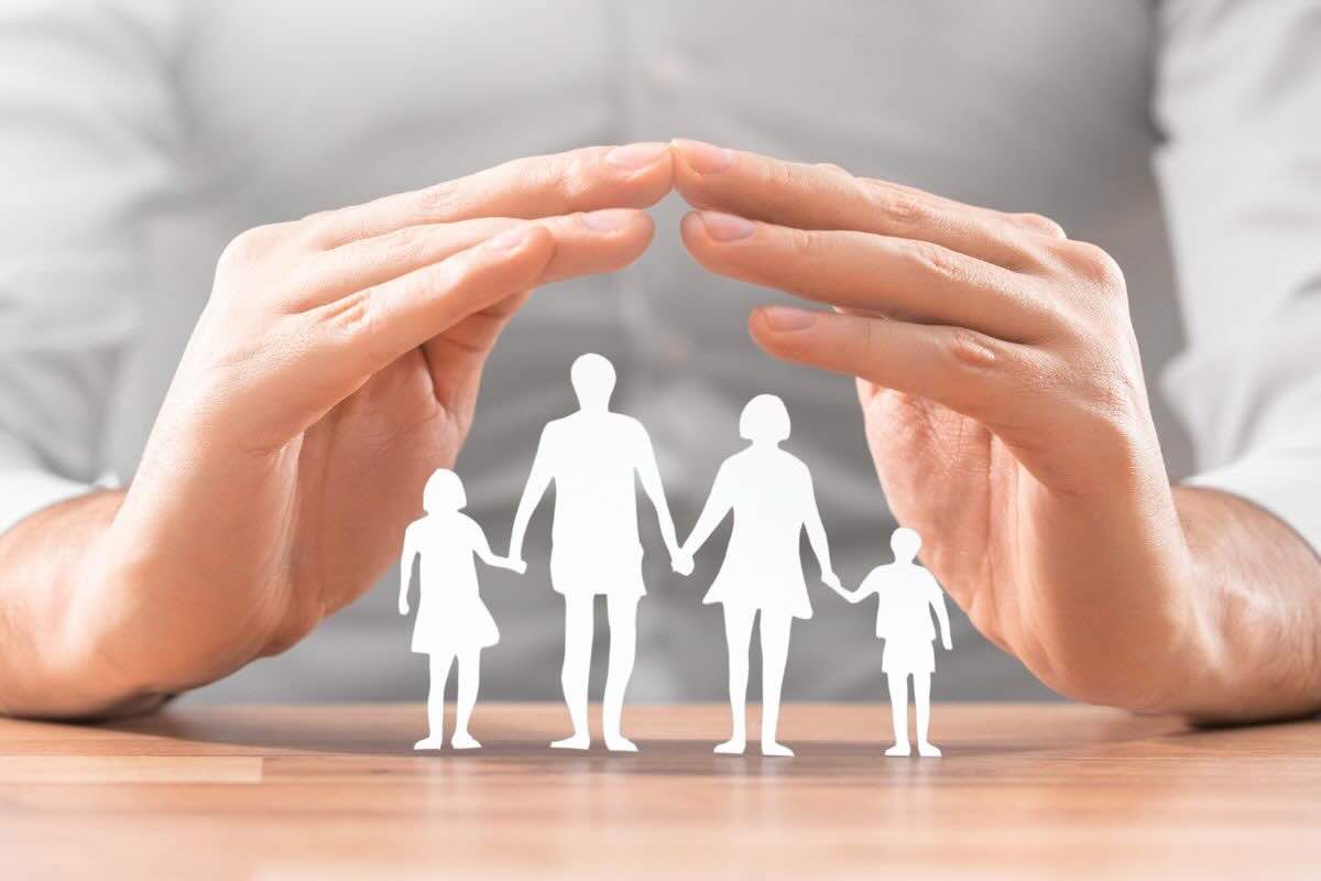 Mani che coprono omini famiglia fatti di carta