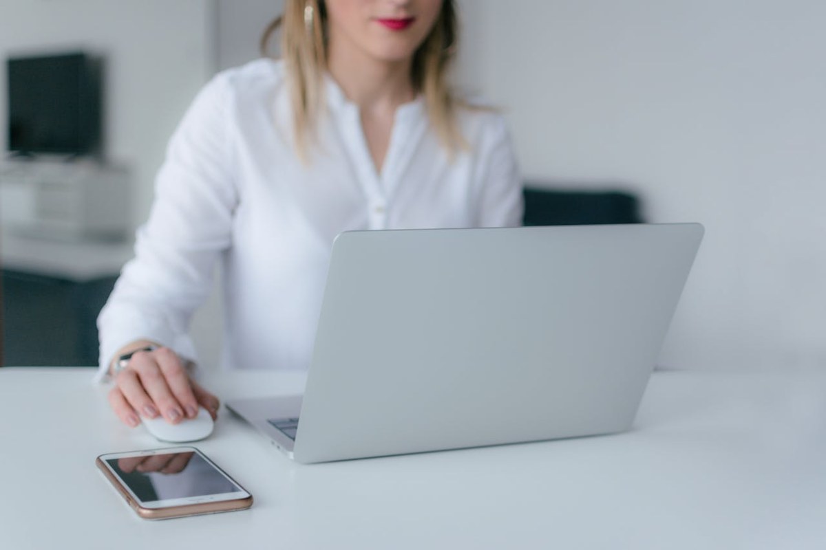 Ragazza al laptop con iPhone sulla scrivania