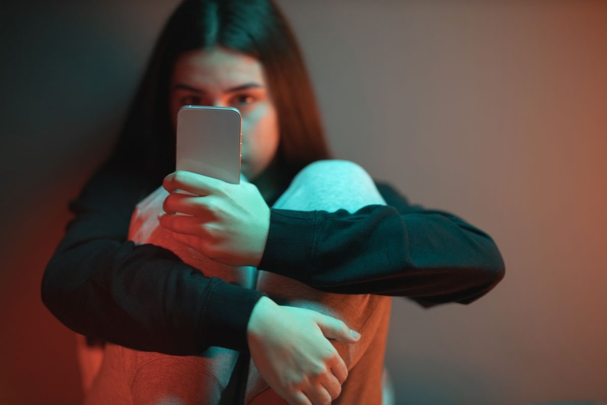 Ragazza guarda smartphone che ha in mano, di fronte al suo viso