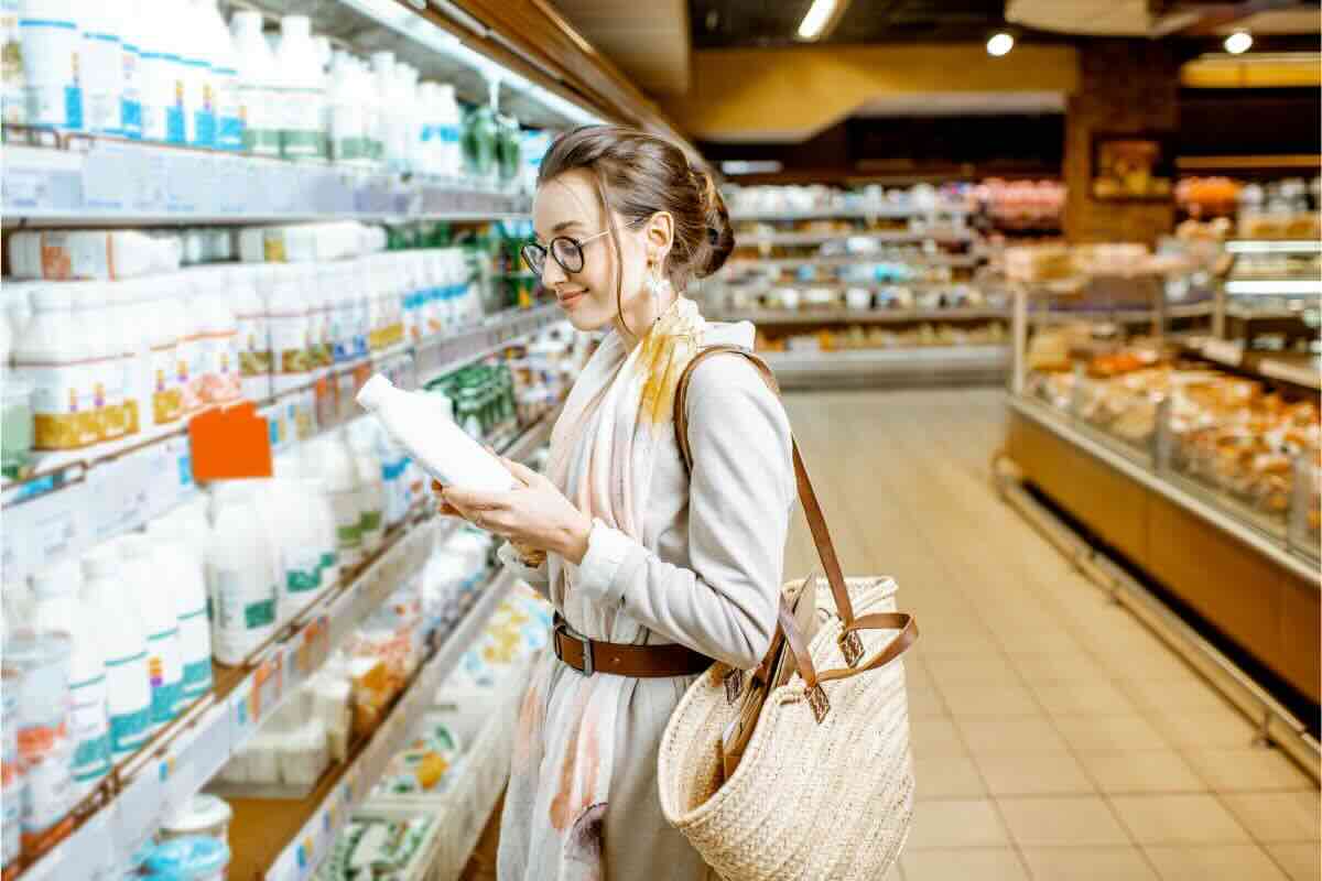 Ragazza scaffale frigo con bottiglia di latte in mano legge etichetta
