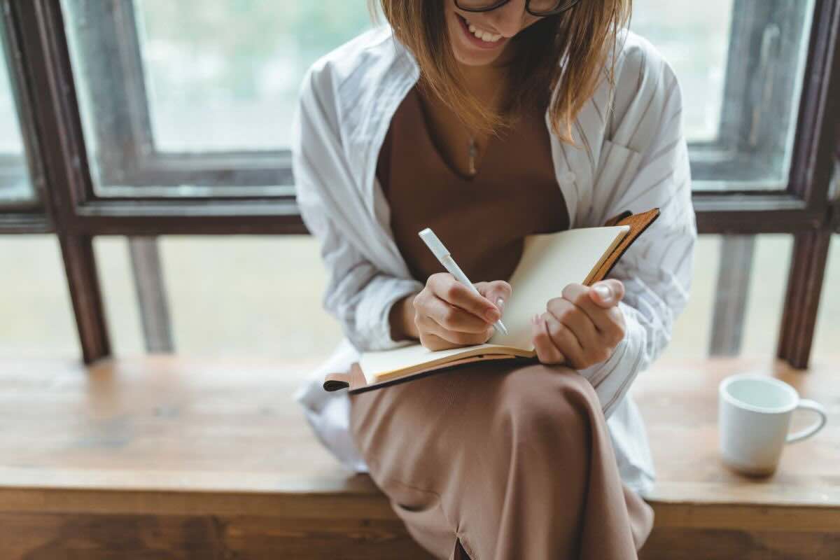 Ragazza felice scrive su quaderno con penna