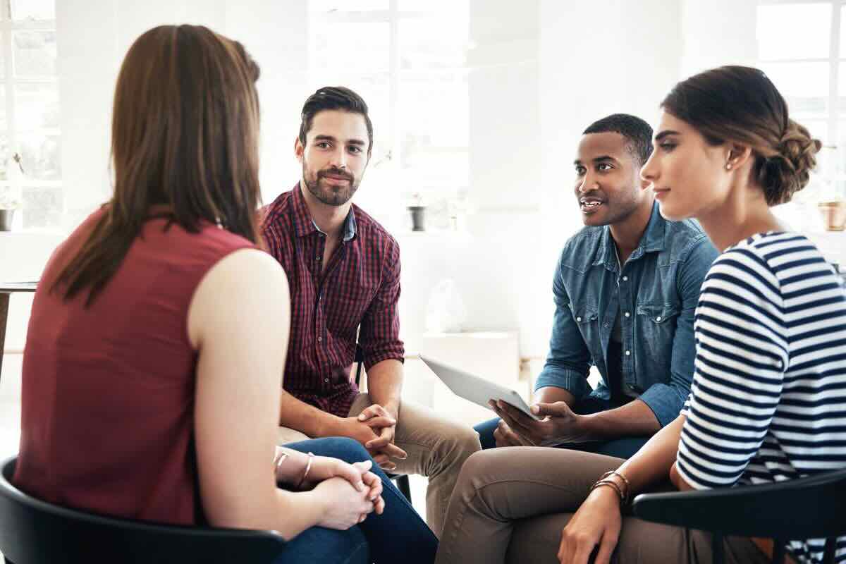 Gruppo di quattro persone riunite in cerchio che chiacchierano