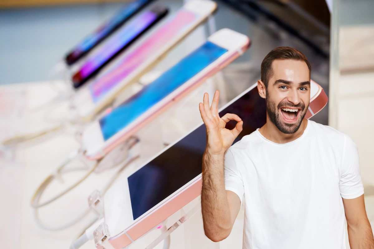uomo che fa il gesto dell'ok sullo sfondo un negozio di cellulari