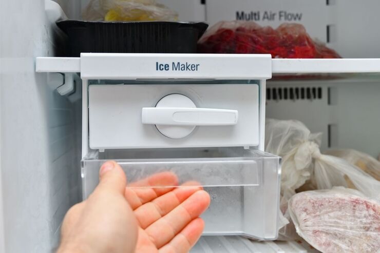 Mano che si avvicina alla manopola della macchina crea ghiaccio del frigo