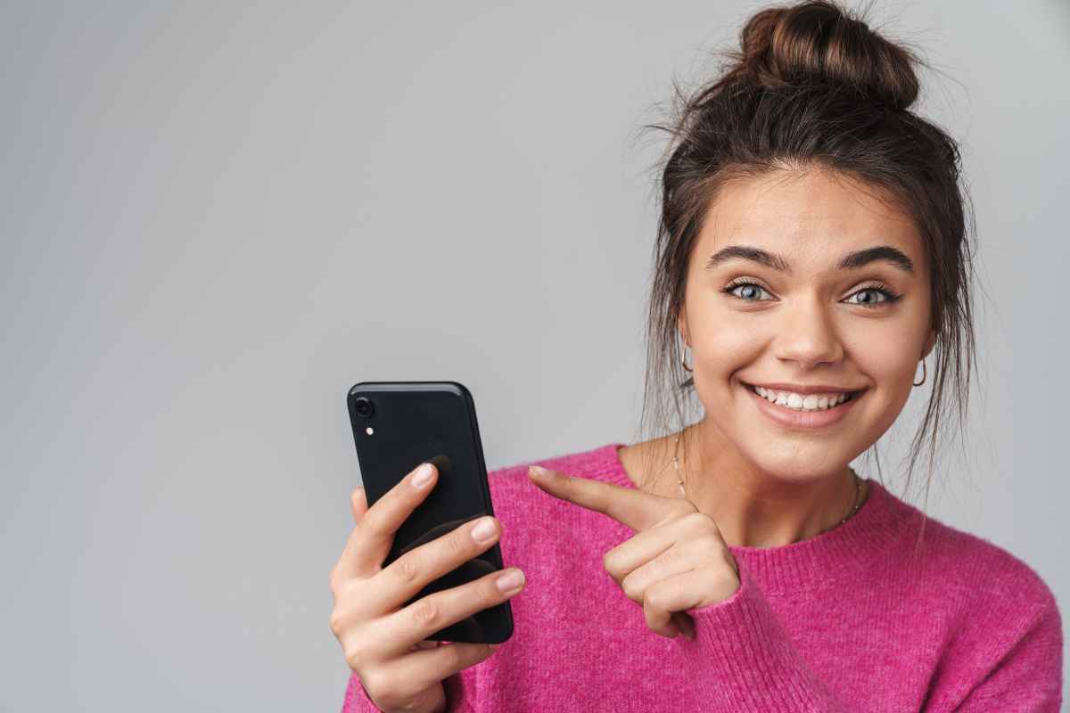 donna che iindica smartphone con un sorriso