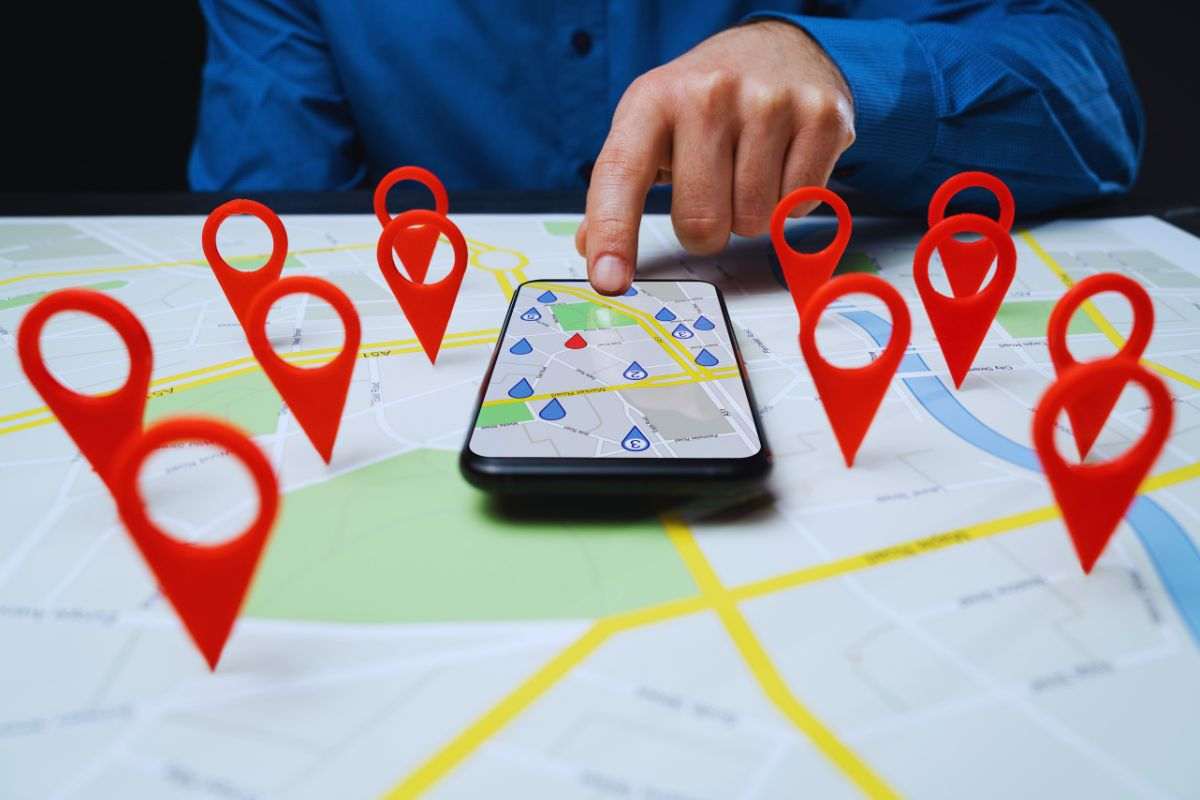 Persona che utilizza navigatore su smartphone sopra cartina fisica