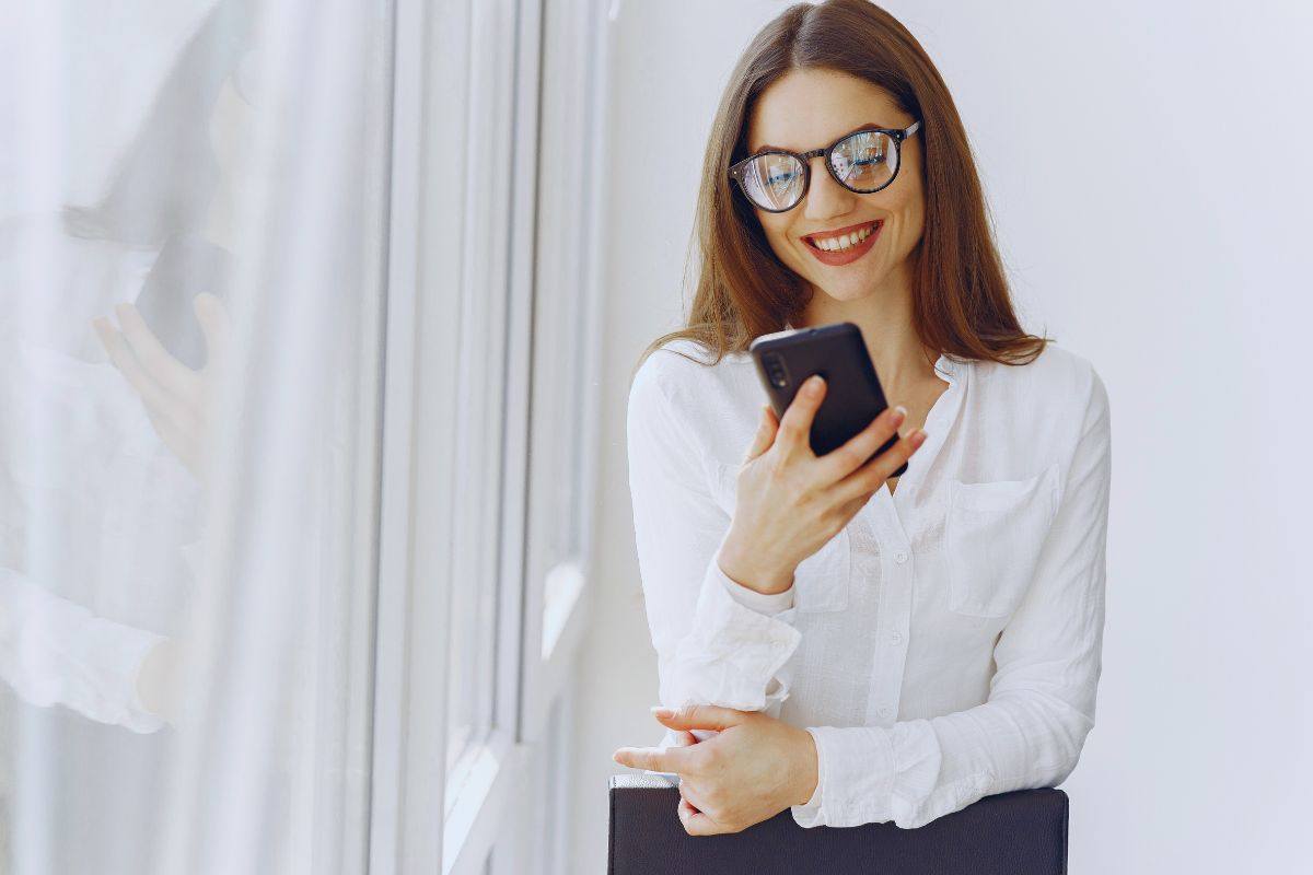 Ragazza sorridente mentre guarda lo smartphone