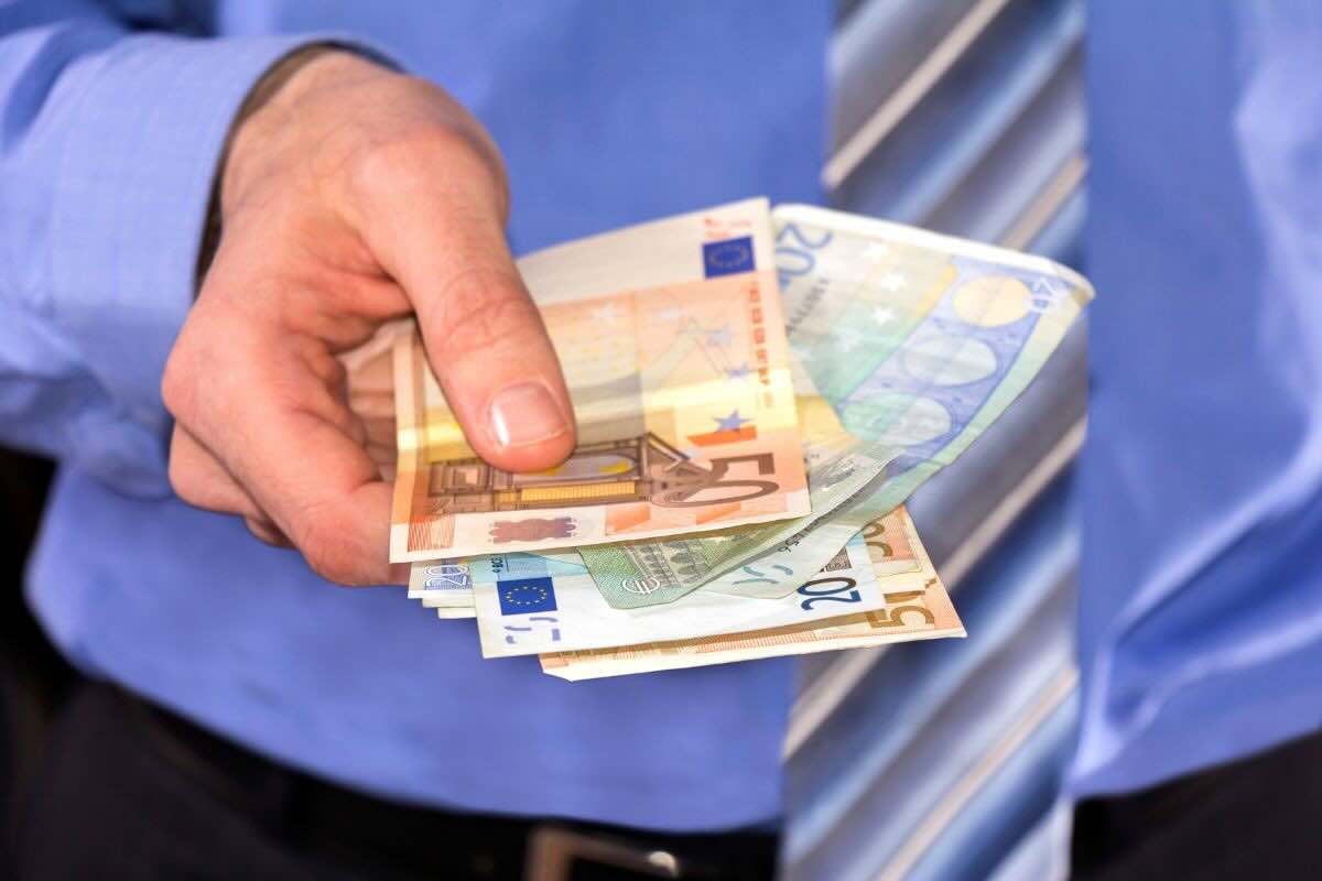 Uomo con camicia con in mano banconote euro