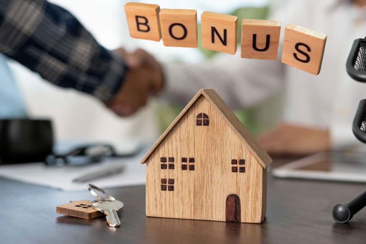 Riproduzione casetta in legno, chiavi, scritta "bonus", sul fondo due persone si stringono la mano