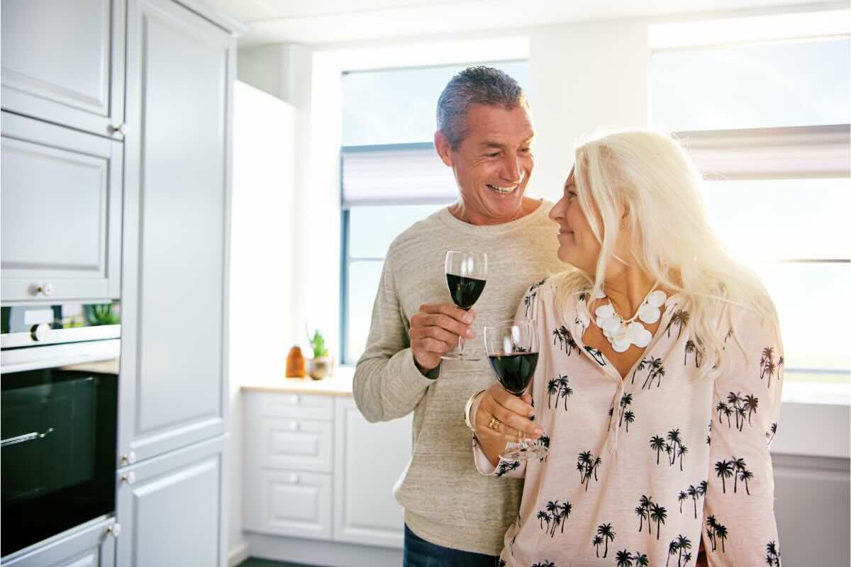 Uomo e donna brindano con vino in casa