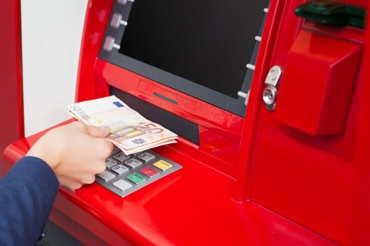 Mano ritira banconote euro da bancomat rosso