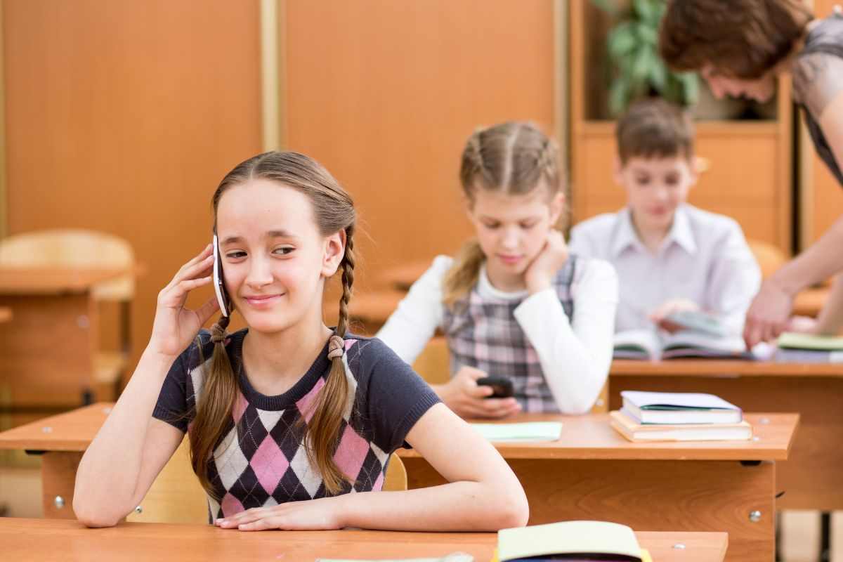 bambina che usa lo smartphone in classe