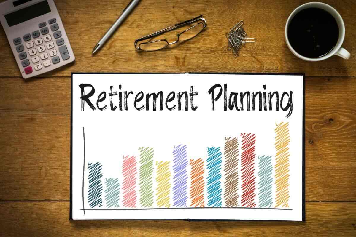 Grafici colorati, scritta "Retirement Planning", occhiali, penna, calcolatrice