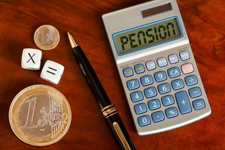 Calcolatrice con scritto "pensione", penna, monete, dati