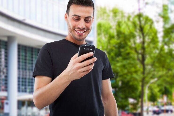 Ragazzo legge messaggi sorridente 