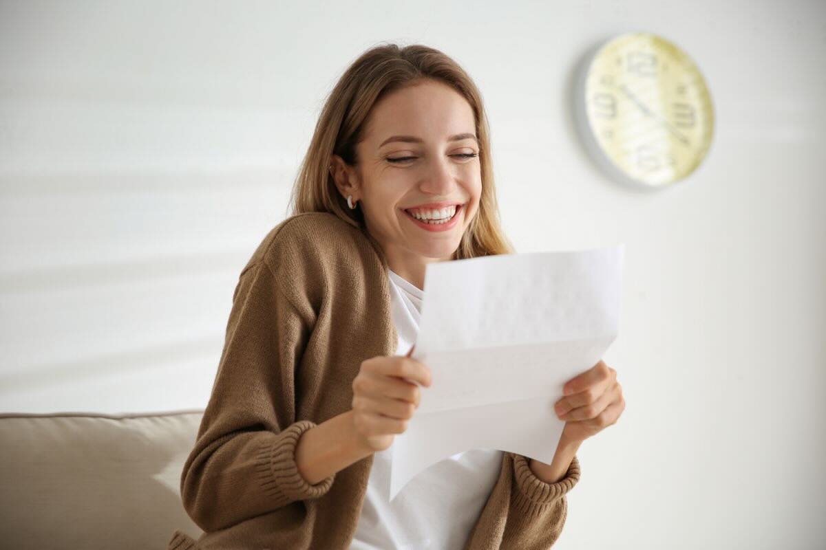 Ragazza felice legge su foglio bianco buone notizie