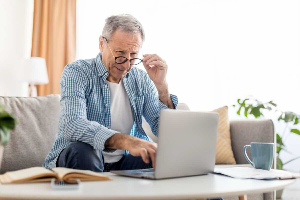 Uomo anziano con occhiali da vista legge qualcosa su PC