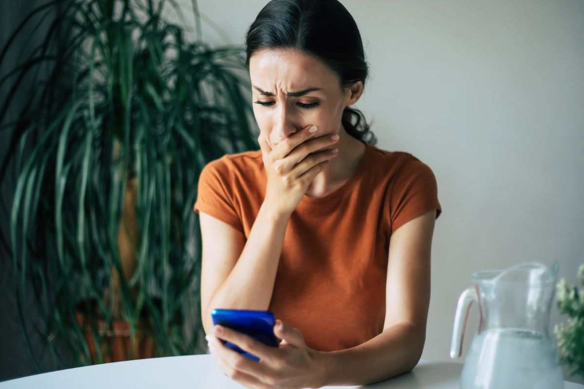 donna disperata che guarda lo smartphone