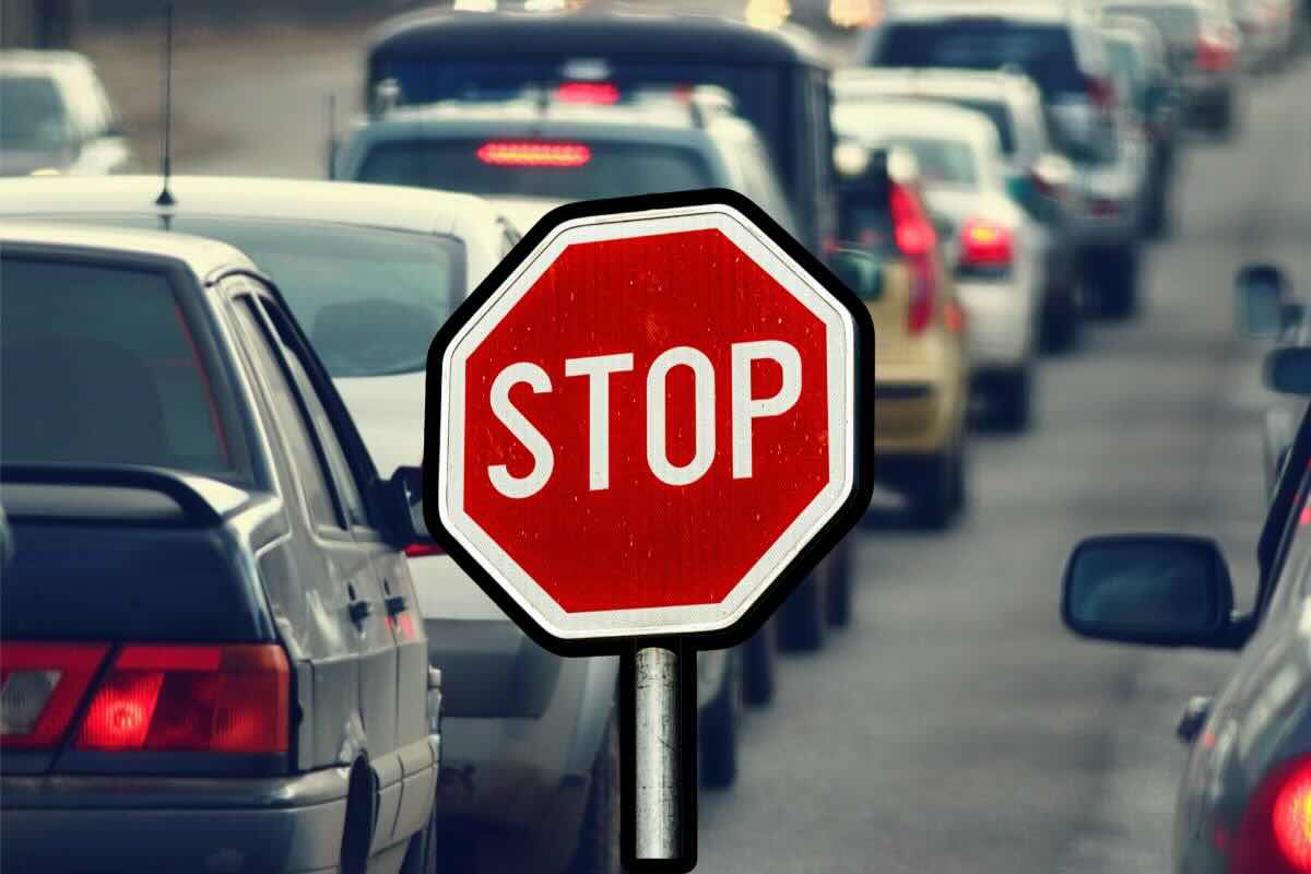 Traffico auto e segnale stop in primo piano
