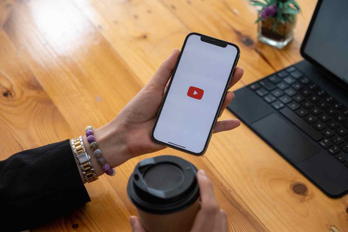 mani che usano cellulare con logo youtube