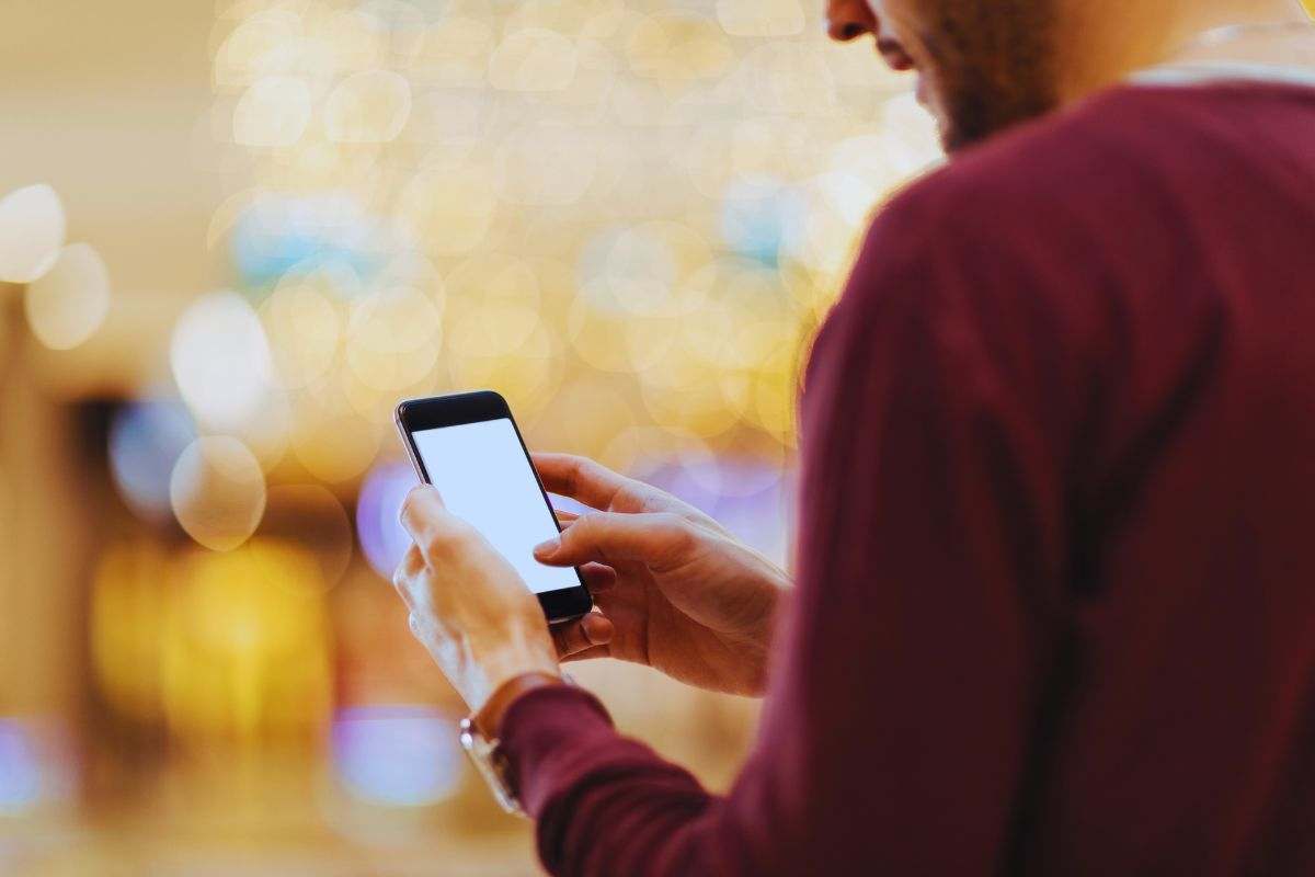 Uomo che guarda schermata bianca su smartphone