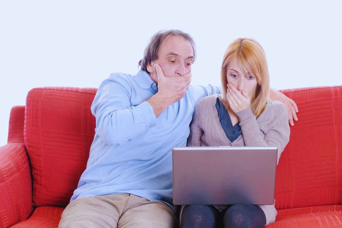 Uomo e donna con espressione stupefatta davanti a portatile