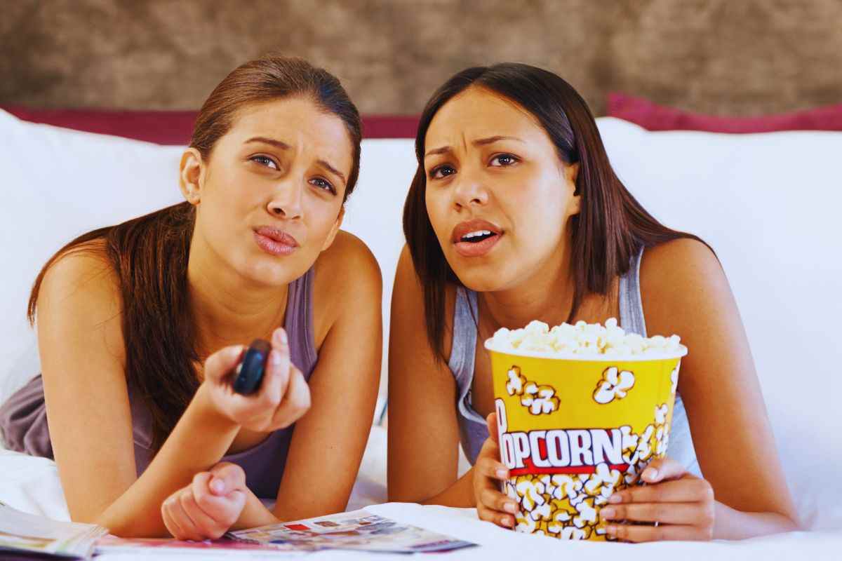 Ragazze distese sul letto che guardano la tv e mangiano pop corn