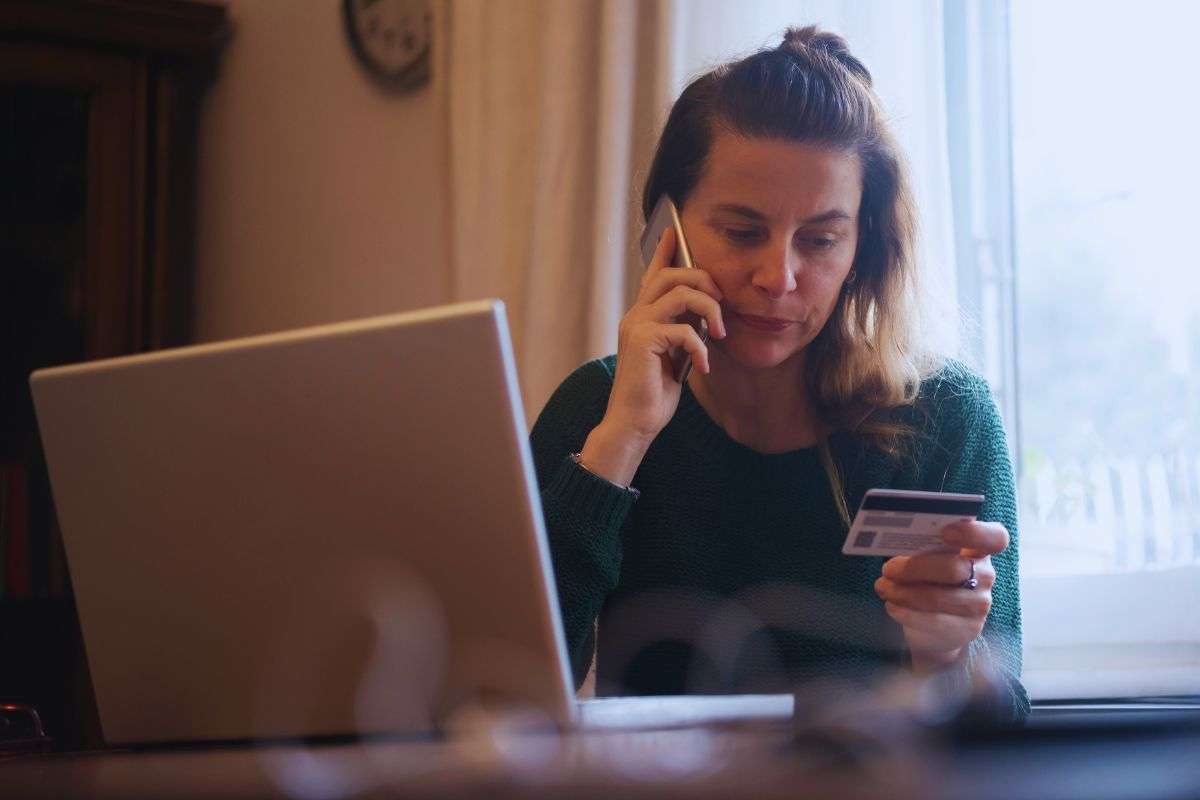 Donna preoccupata al telefono guarda i dati della carta di credito