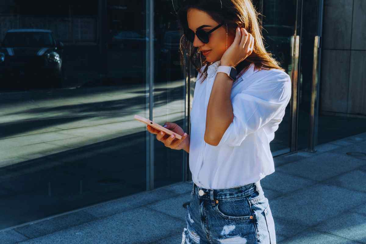 Ragazza che cammina in strada guardando il suo iPhone