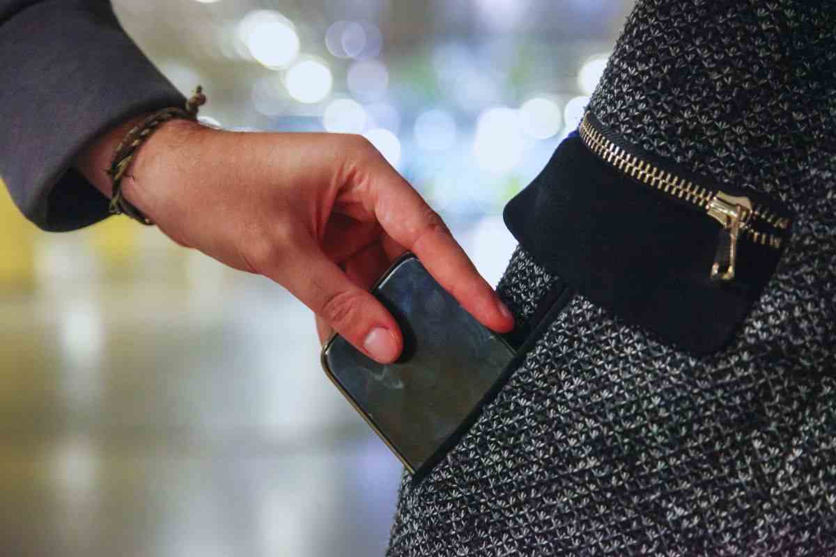Uomo che ruba un telefono dalla tasca di un giubbotto