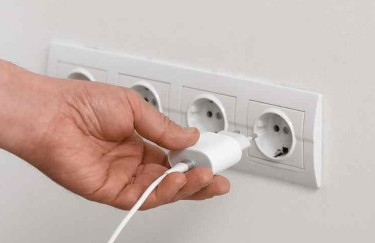 ano che infila un caricabatterie in una presa