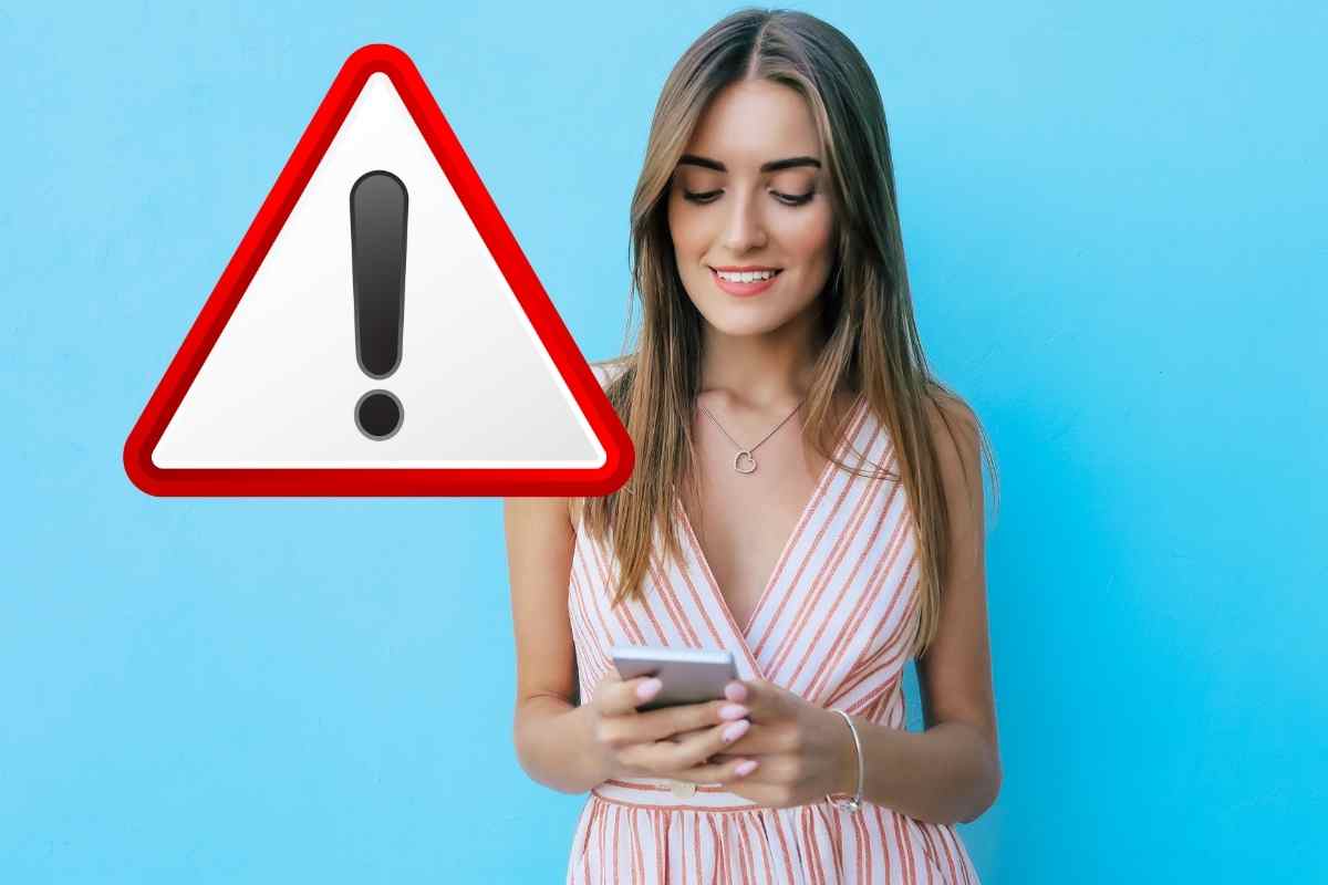donna con smartphone e segnale di pericolo