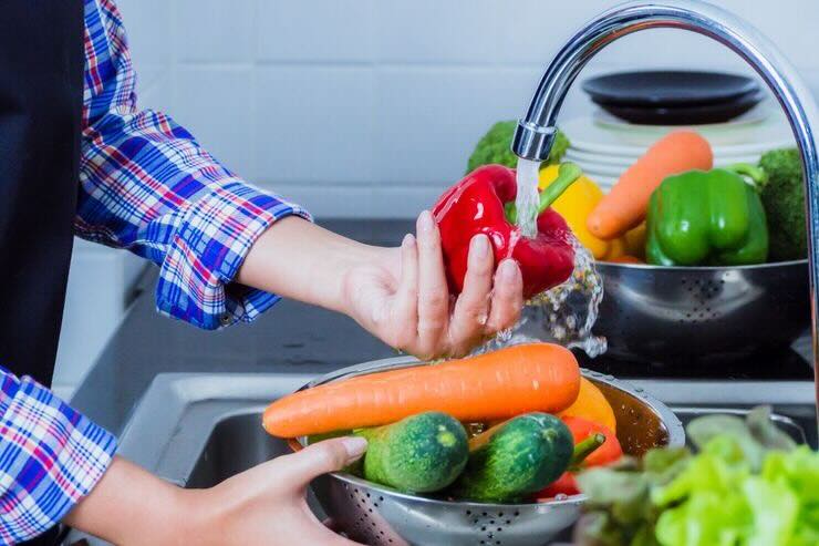 Lavare peperone sotto acqua corrente, altra verdura come carote, cetrioli