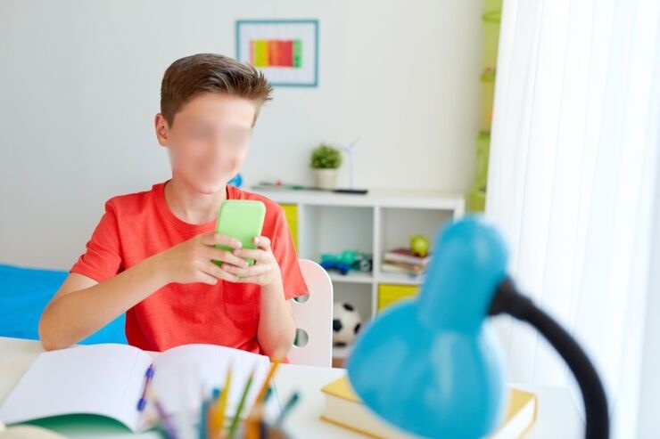 Bambino alla scrivania con smartphone