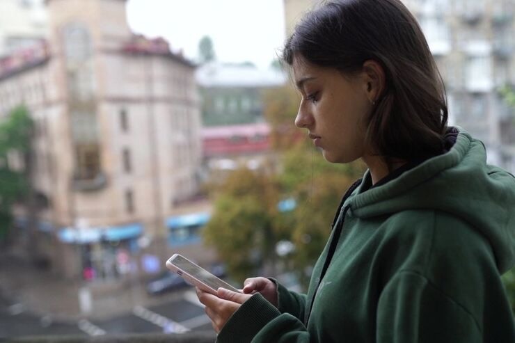Ragazza legge messaggio sul cellulare, sguardo triste