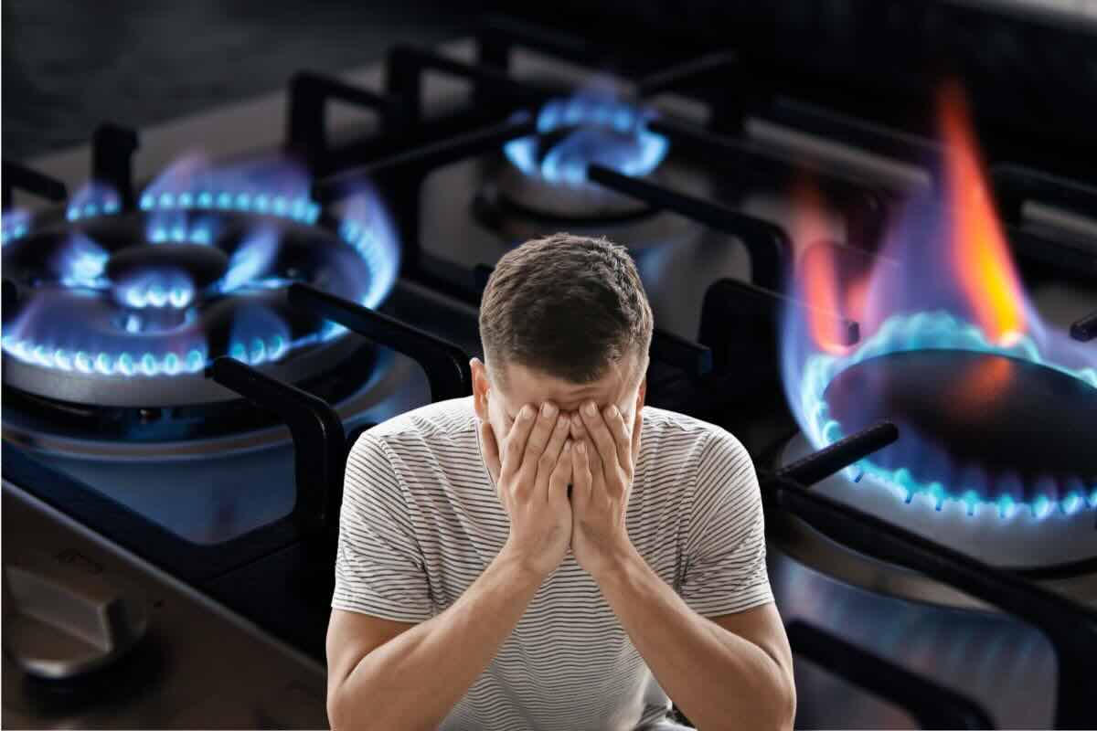 Uomo mani sul viso, sul fondo fornelli del gas accesi