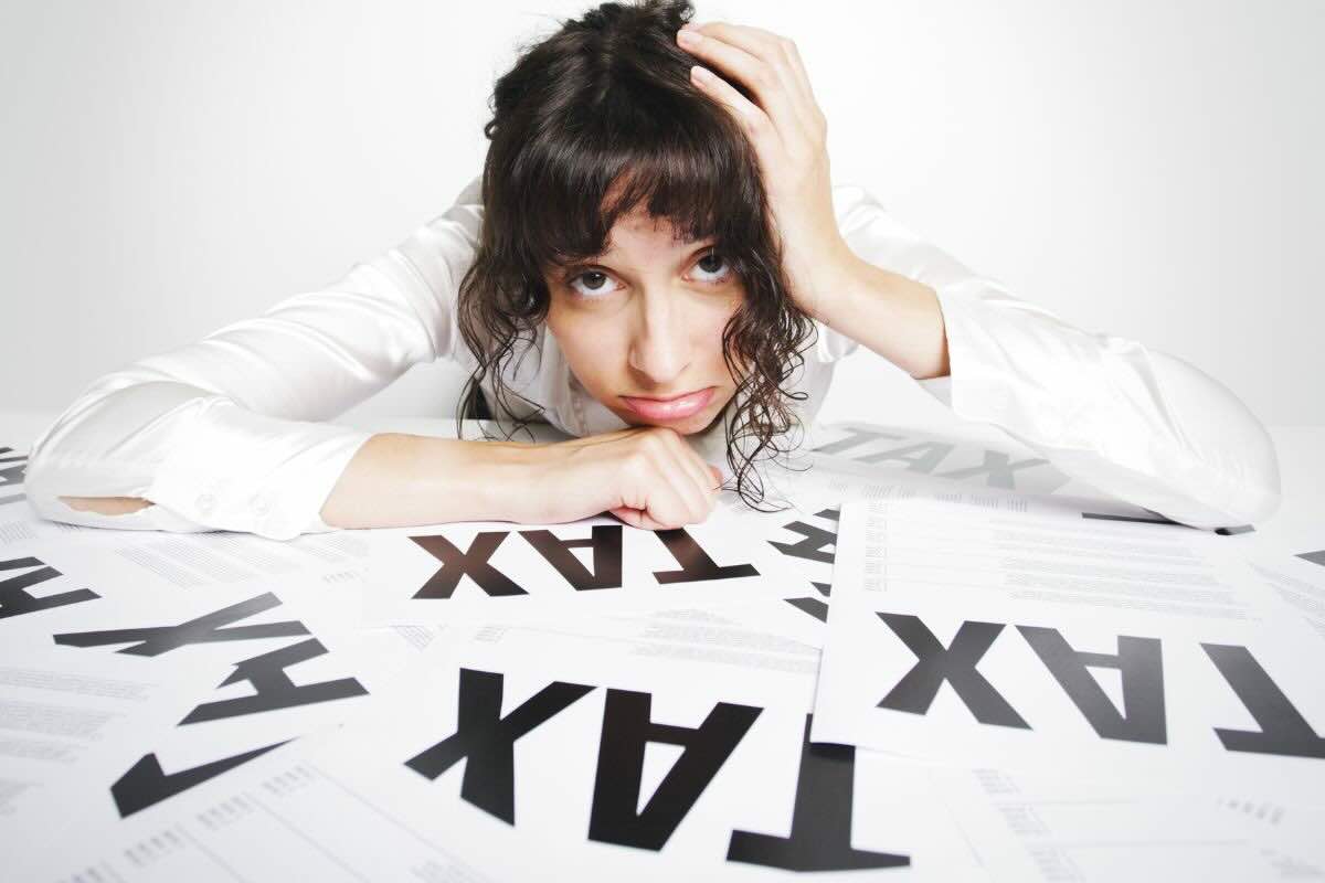 Ragazza triste su fogli con scritto "Tax"
