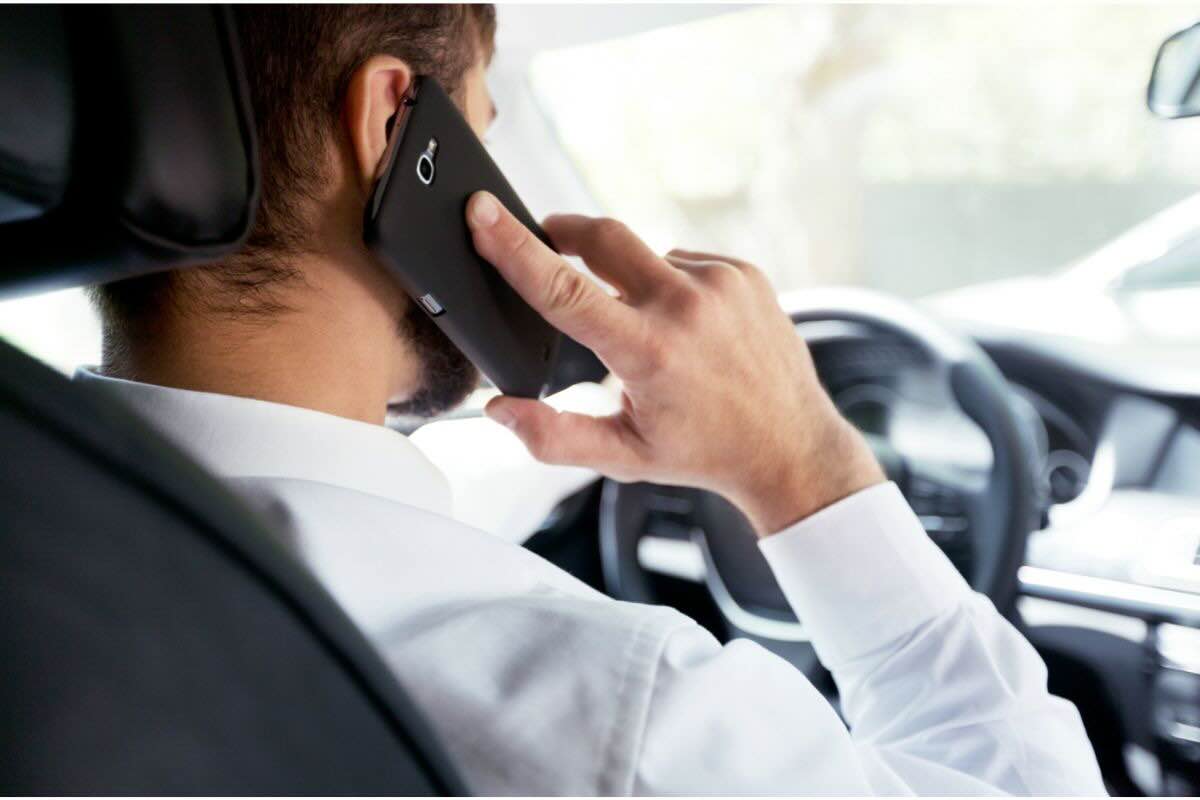 Uomo con telefono all'orecchio alla guida