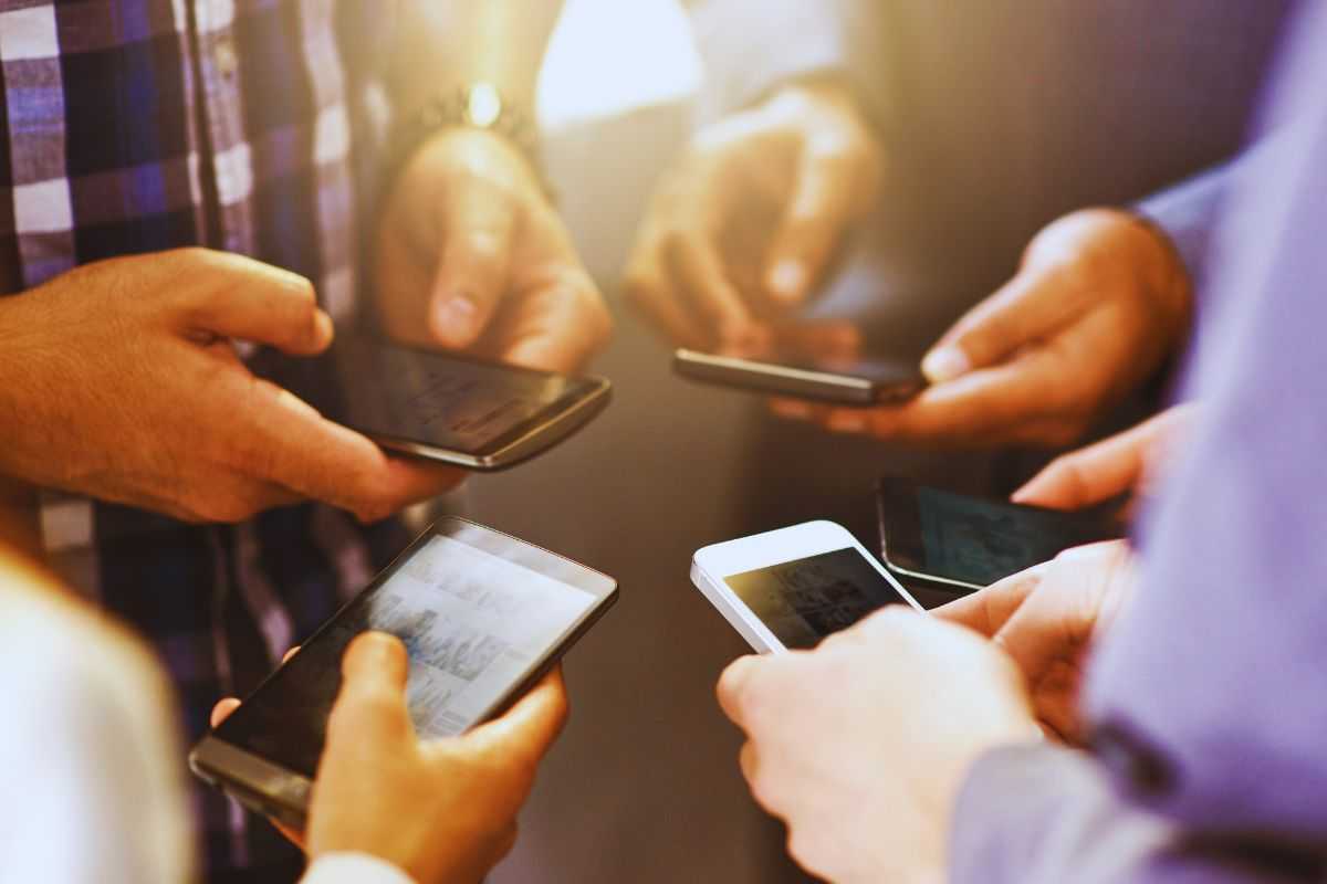 Gruppo di persone in cerchio con smartphone in mano