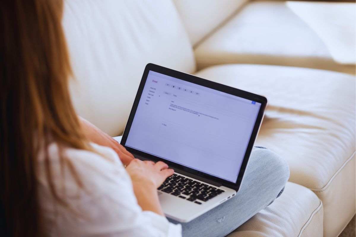 Donna di spalle che scrive una mail al pc