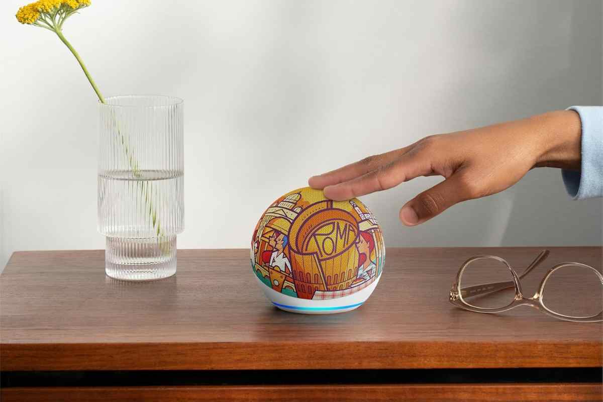Mano su Echo Dot Roma che si trova su un tavolo